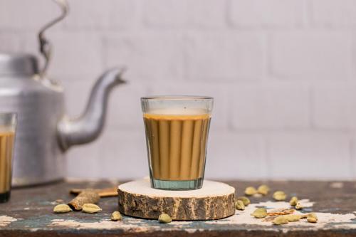 Indian chai in glass cups with metal kettle and other masalas to