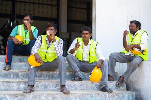 Group of Industrial workers having tea or coffee during break - concept of relaxation, coworkers and blue collar jobs